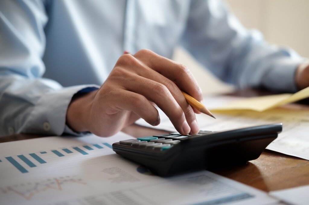 Business man using calculator and laptop on white desk, Accounting and tax concept